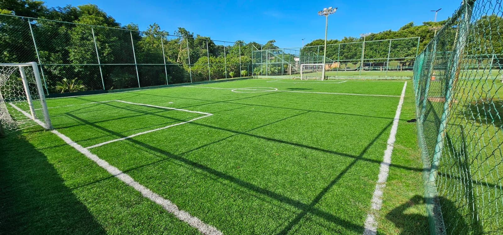 Vista panorâmica de campo esportivo em área residencial, com linhas de campo, horizonte e céu